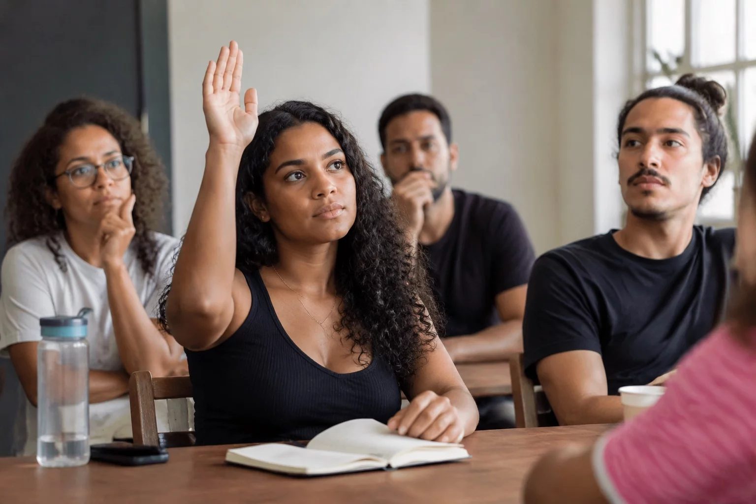 Estudante levantando a mão em uma mesa de seminário coberta de anotações